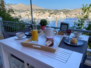 een tafel met een dienblad met ontbijtproducten op een balkon bij Thodoris Infinity View Apartments in Symi