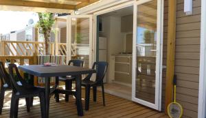 a patio with a table and chairs on a deck at Camping Paradis Aloé in Médis