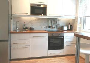 a kitchen with white cabinets and a sink and a microwave at 4-Zimmer Haus in Leipzig in Leipzig