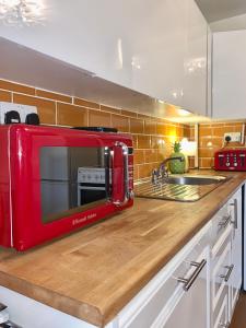 un microondas rojo sentado en la parte superior de una barra de cocina en Great 2 bedrooms apartment 15 mins from the centre, en Londres