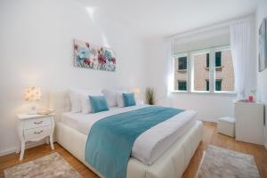 a white bedroom with a large bed and a window at Sun Spalato City in Split