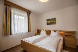 sypialnia z łóżkiem z białą pościelą i oknem w obiekcie App. Miara - Ciasa Lavarella w mieście San Vigilio di Marebbe