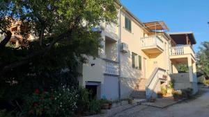 a white house with stairs and balconies on a street at Apartmani Krpeta in Pakoštane