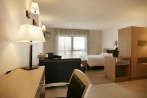 Habitación de hotel con cama, sofá y lámpara en Les Logis D'Espale en Sausheim