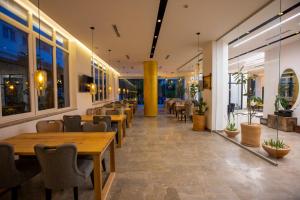 a restaurant with wooden tables and chairs and windows at Hotel Mille Amici in Shëngjin