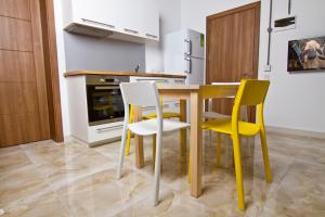 a kitchen with a wooden table and yellow chairs at Cresta Beach Studios in St. Julianʼs