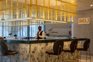 un homme debout derrière un bar avec des chaises dans un restaurant dans l'établissement The Leonardo, à Johannesbourg
