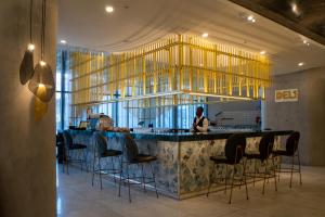 a restaurant with a bar with chairs and a woman at The Leonardo in Johannesburg