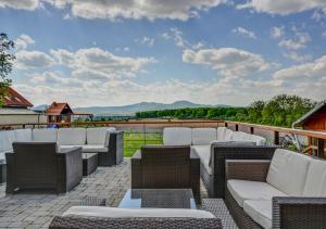 un patio con sillas blancas y mesas en un balcón en Penzión TOKAJ MACIK WINERY Guesthouse, en Malá Tŕňa