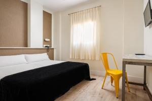 a bedroom with a bed and a desk and a yellow chair at YIT Casablanca in Granada