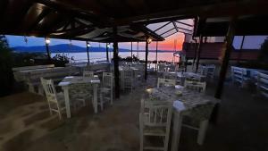 restauracja z białymi stołami i krzesłami oraz oceanem w obiekcie ORION Guest House w mieście Sozopol