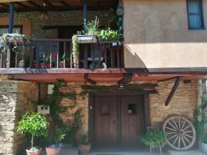 a building with a balcony and a wooden door with potted plants at Las 3 Negrillas in Toral de Merayo