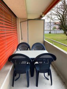 una mesa y 2 sillas en un porche con ventana en Serviced Apartments Haus 2, en Uzwil