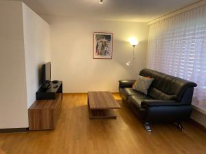 a living room with a leather couch and a coffee table at Serviced Apartments Haus 2 in Uzwil