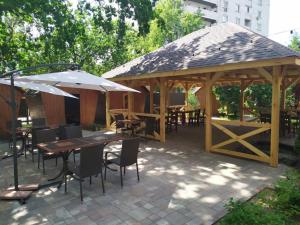 a wooden pavilion with tables and chairs and an umbrella at Готельний комплекс Самікс in Kyiv