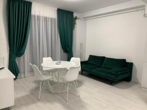 a living room with a green couch and a table and chairs at Apartament Alexandra in Mamaia