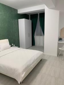 a bedroom with a white bed and a green wall at Apartament Alexandra in Mamaia