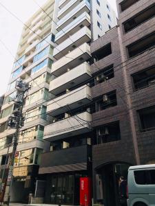 a tallartment building with a van parked in front of it at LANG Hotel GINZA 1K in Tokyo