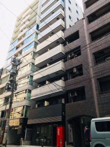 a tallartment building with a van parked in front of it at LANG Hotel GINZA 1K with Kitchen 從東銀座站步行3分鐘 帶廚房 हिगाशी गिन्ज़ा स्टेशन से 3 मिनट की पैदल दूरी पर रसोई के साथ in Tokyo