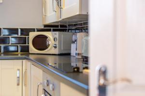 a kitchen with white cabinets and a microwave at Church View Apartments in Weymouth