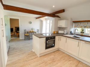 a kitchen with white cabinets and wooden floors at Ysgubor Ucha in Ruthin