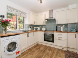 a kitchen with white cabinets and a washer and dryer at Hunters Cottage in Highpeak Junction