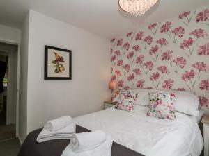 a bedroom with a white bed with pink floral wallpaper at Hunters Cottage in Highpeak Junction