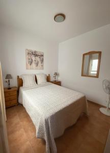 a white bedroom with a bed and a mirror at Ático Los Ángeles Min 3 nights in Puerto de Santiago