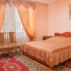 a bedroom with a bed and two chairs and a window at Готельний комплекс Самікс in Kyiv