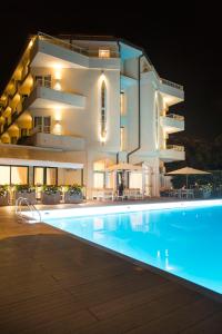 a large building with a swimming pool at night at Grand Hotel in Forte dei Marmi