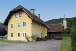 a yellow house with a table and a church at GÄSTEHAUS HARTL - Gasthof Hartl, vlg Zum Wirt in Neuhaus