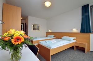a room with two beds and a vase of flowers at Wasserburg Rindern in Kleve