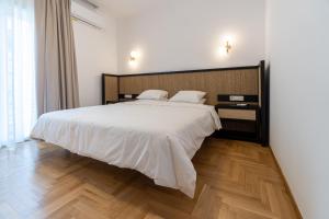 Schlafzimmer mit einem großen weißen Bett und Holzboden in der Unterkunft iKu Urban Apartment in Kavala