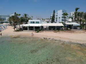 a view of a beach with a building and the water at Karousos Beach Rooms in Ayia Napa