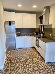 a kitchen with white cabinets and a stainless steel refrigerator at Galería de Cervantes in Toledo