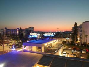 a building with a blue roof in a parking lot at Karousos Beach Rooms in Ayia Napa