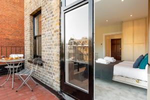 a room with a brick wall and a bedroom at CAPITAL Sloane Street Studio with Balcony in London