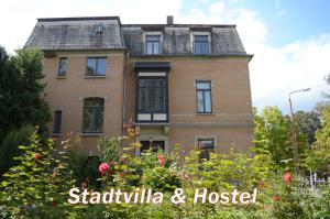 a house with a large window and a large building behind it at Hummel Hostel - Historische Stadtvilla mit Garten in Weimar