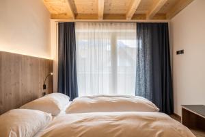 two beds in a bedroom with a window at App. Pedagà - Ciasa Lavarella in San Vigilio Di Marebbe