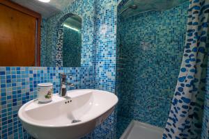 a blue tiled bathroom with a sink and a mirror at La Casetta Azzurra NAXOS in Giardini Naxos