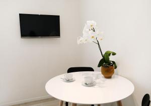 un tavolo bianco con due tazze e un vaso con fiori bianchi di b&b boutique suite bari a Bari
