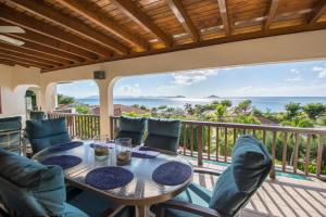 a table and chairs on a balcony with a view of the ocean at LOBLOLLY in Virgin Gorda