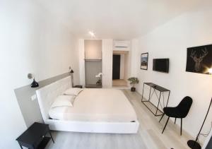 een witte slaapkamer met een wit bed en een zwarte stoel bij b&b boutique four rooms bari in Bari