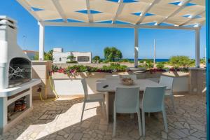 un patio con mesa, sillas y chimenea en La Maison Blue Salento - Villetta e monolocale fronte e vista mare, en Torre San Giovanni