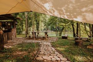 a picnic table with an umbrella in a park at Robinson camp Kupa - Juratovićki brig in Netretić