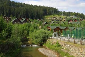a village with a river next to a forest at Bukovel Hotel in Bukovel