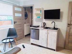 a living room with a kitchen with a tv on the wall at Villa Río Mielno in Mielno