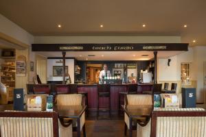 un bar dans un restaurant avec un homme debout derrière le comptoir dans l'établissement Connemara Coast Hotel, à Furbo