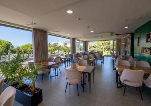 um restaurante com mesas, cadeiras e janelas em Olive Nature - Hotel & SPA da Quinta Dona Adelaide em Valpaços