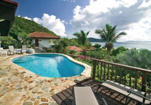 a swimming pool in front of a house with the ocean at VILLA VALMARC in Virgin Gorda